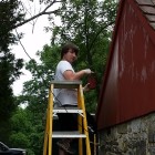 Apprentice Tyler Walton applies paint to the Bertolet Bake House at Daniel Boone Homestead, Birdsboro (PHMC staff)