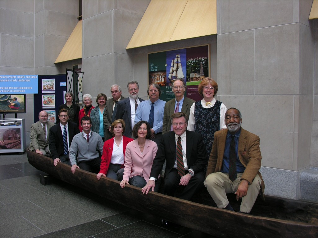Members of the Historic Preservation Board pose for a photo with the dugout canoe exhibit in 2007. [Standing L to R: Janet Irons, Ann Greene, Cecilia Rusnak, Bruce Thomas, Michael Eversmeyer, Scott Heberling, Charles Hardy, III, Jean Cutler (Director, BHP). Riding in the canoe L to R: Kurt Carr (BHP staff), Jeff Kidder, Scott Standish, Patricia Gibble, Sandra Lee Rosenberg, John Milner (Chair), Emanuel Kelly.]