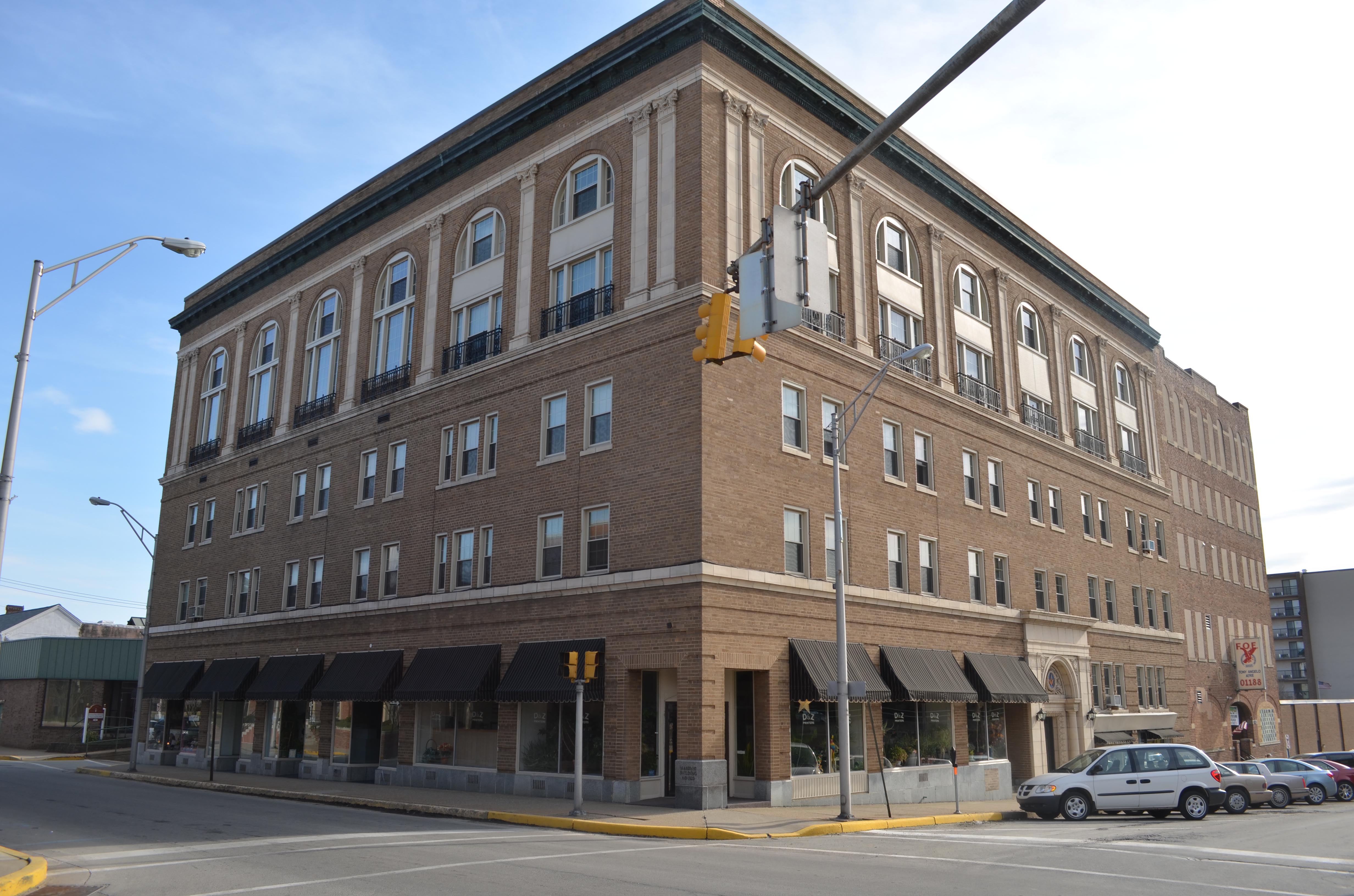 Large 5-story brick building at the corner of two city streets.