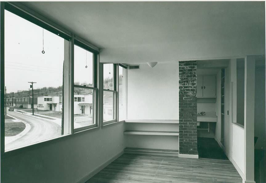 Historic photo of a completed home’s interior, looking from the dining area out to the curving street. Often defense-related housing was intended to provide a temporary solution to housing demands, but these homes were designed to be permanent and featured the modern conveniences of the period.  Image courtesy of the Louis I. Kahn Collection, University of Pennsylvania Architectural Archives.