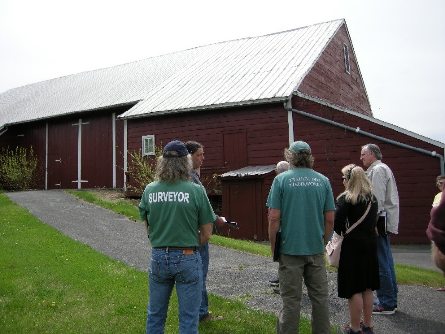 People standing in grass in front of large wood building.