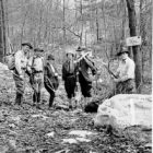 Black and white photo of men clearing trail in the woods