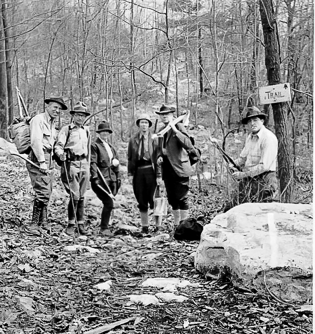 Black and white photo of men clearing trail in the woods