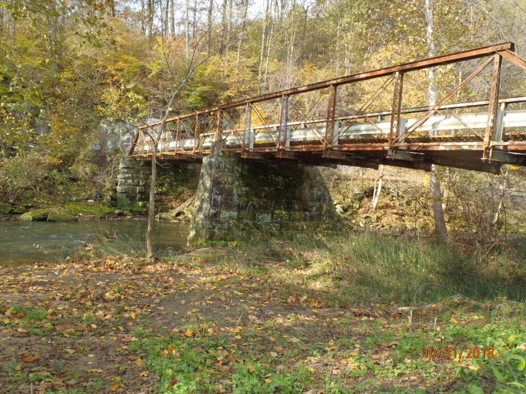 Metal truss bridge, view from stream bank