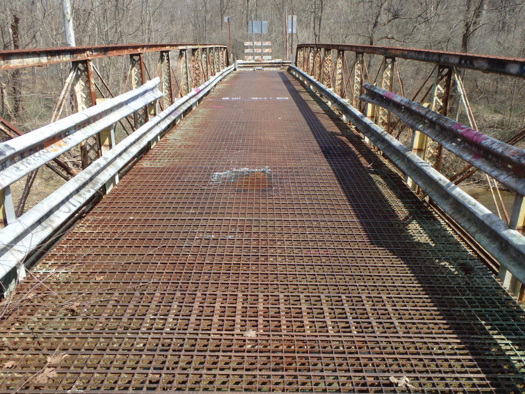 Metal truss bridge with deteriorated decking.