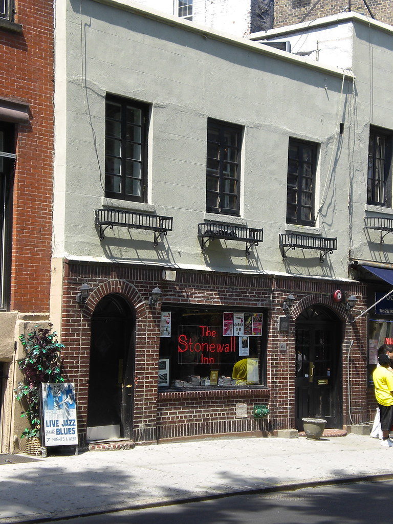 A street view of Stonewall Inn with a neon sign in the window which reads “The Stonewall Inn.”