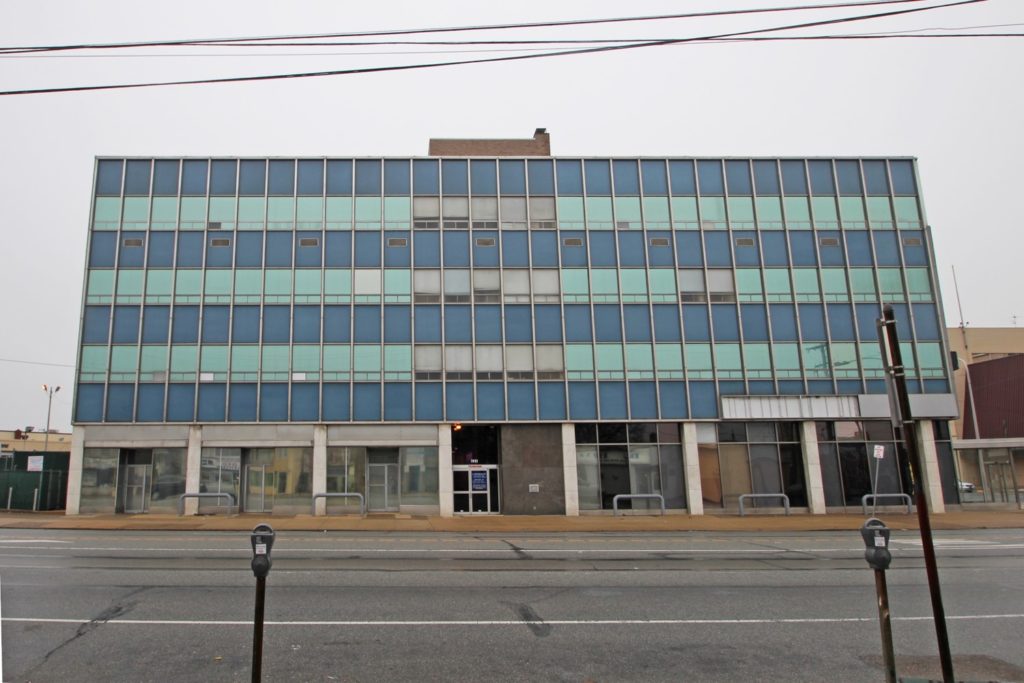 Large rectangular glass building along street.