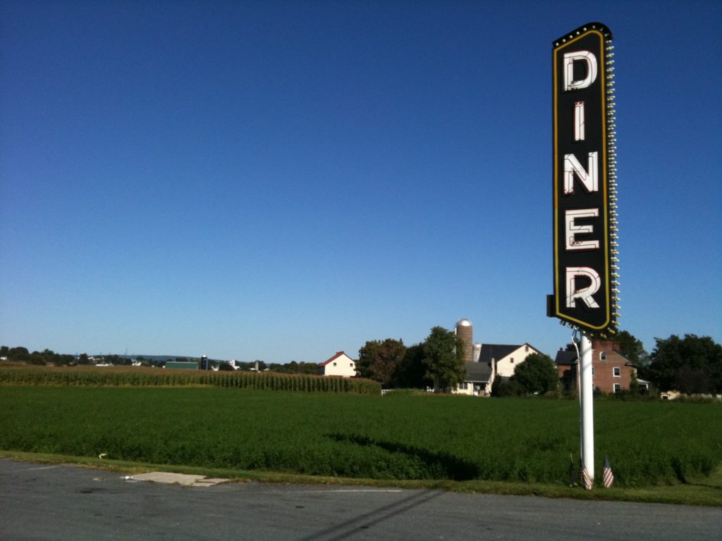Farm with crops and a large sign for a diner.