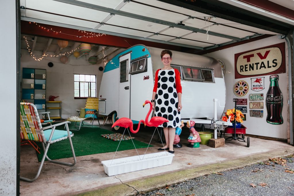 Woman standing in front of camper in a garage.