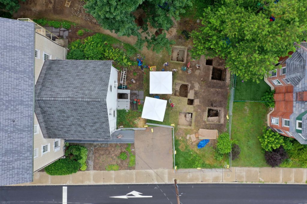 Looking down at roof of building and several large square holes in a yard.