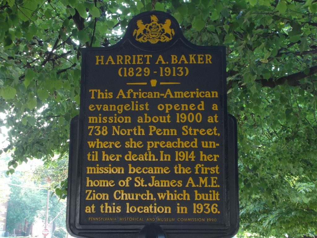 Large blue metal sign with yellow writing for Harriet A. Baker.