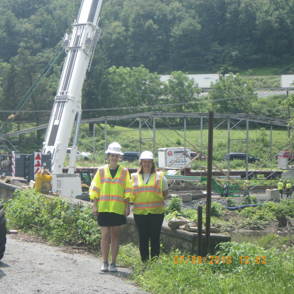 Two people standing outside in front of a mechanical crane.