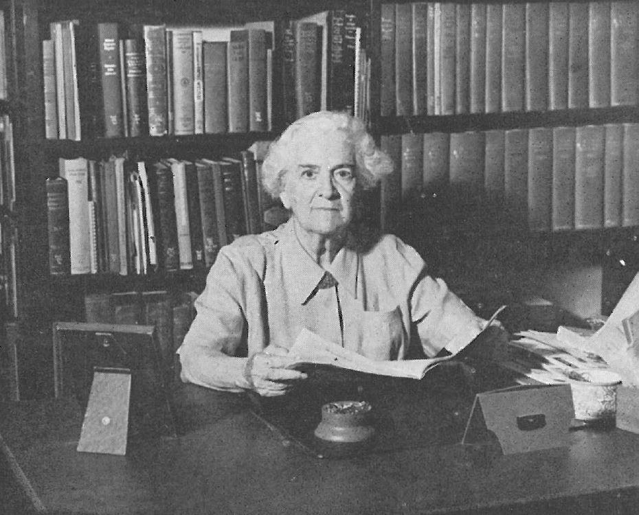 Woman sitting at a desk reading books.