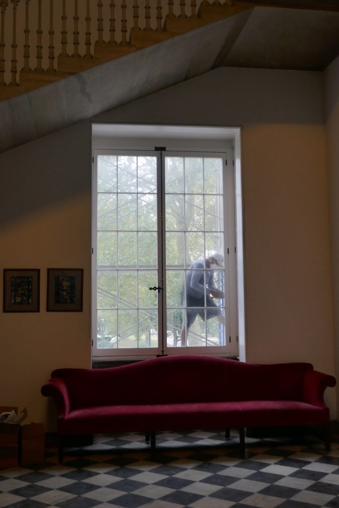 Man working on tall wood window.