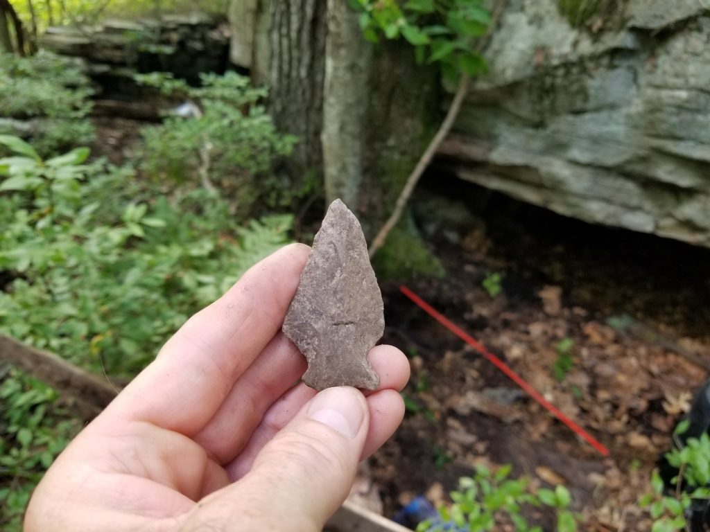 Hand holding rock spear point.