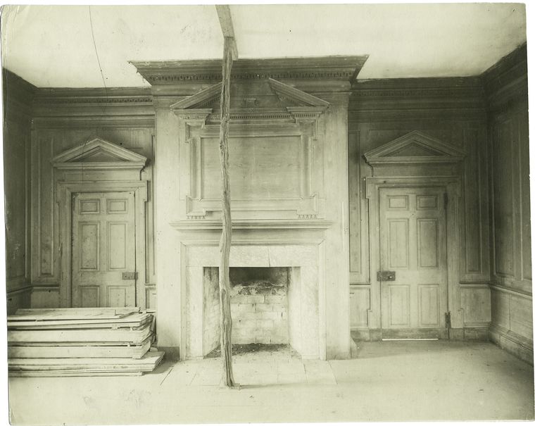 Black and white photo of a room with fireplace and two doors.