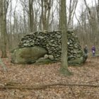 Large pile of small stones around a large boulder in woods