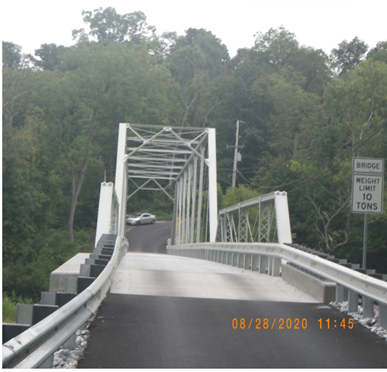 Road going through metal truss bridge.