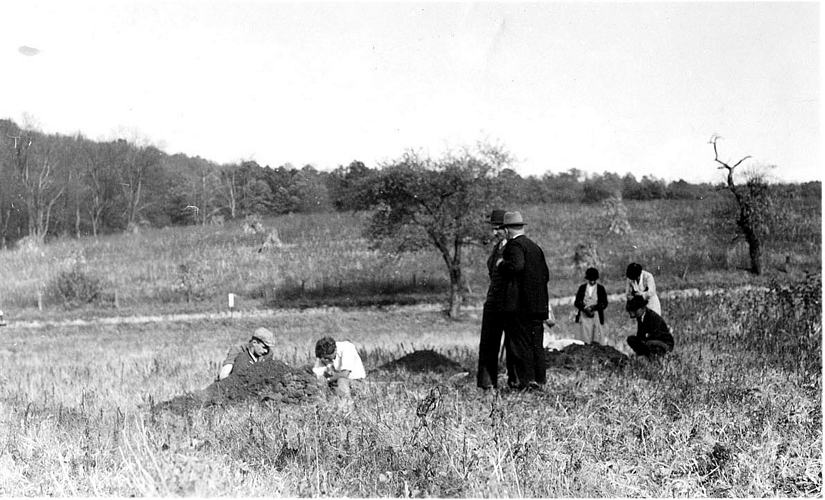 Black and white photograph of men standing in field.