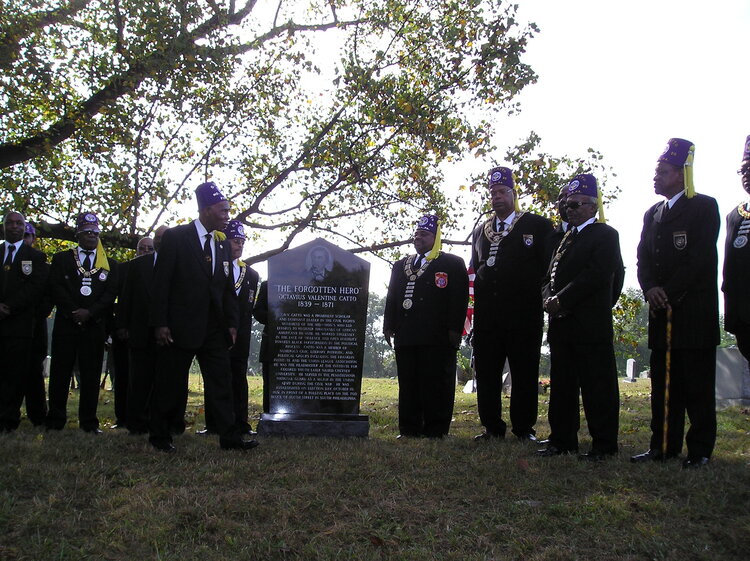 Group of African American men gathered around the O.V. Catto memorial marker.