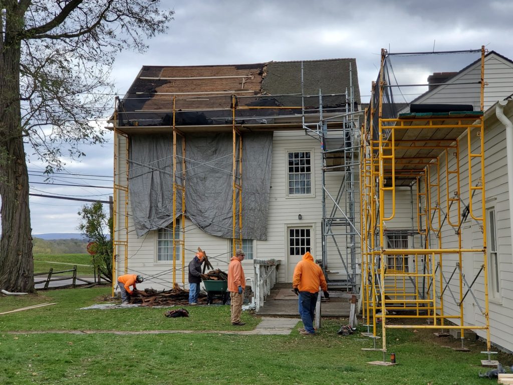 Men standing next to house with scaffolding.