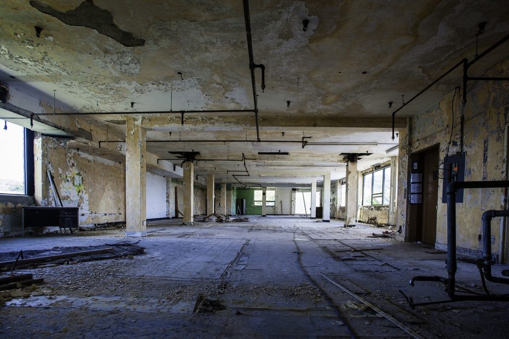 Large open interior space with peeling plaster and missing windows.