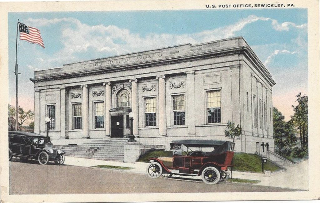 Colorized postcard of large white stone building with two older cars at street.