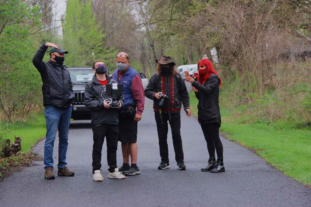Group of people standing in a road with cameras and equipment.