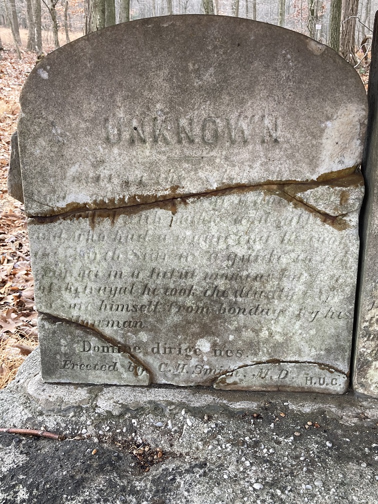 Broken grave stone with faded inscription for "Unknown".