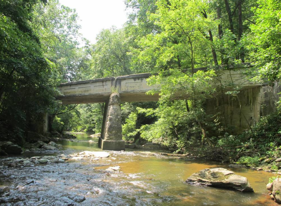 Concrete bridge over stream and supported by tall concrete piers.