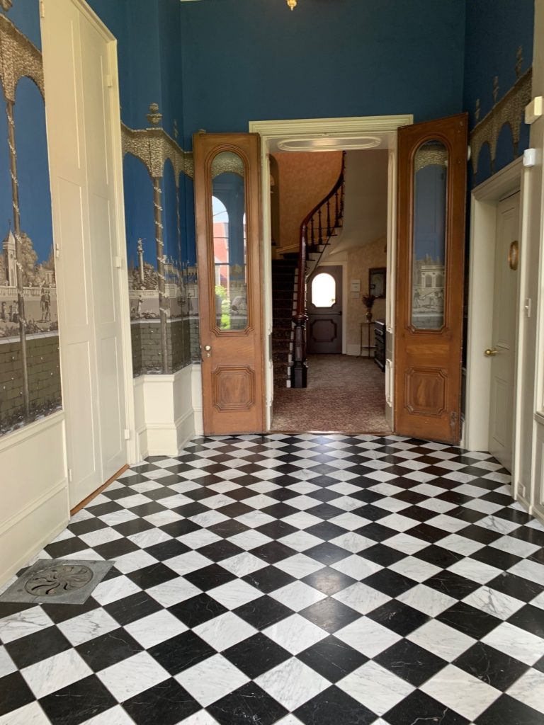 Narrow room with black and white checkerboard floor and colorful walls.