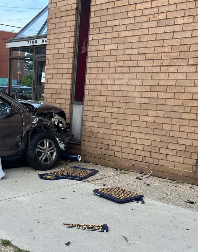 Car with damaged front next to a brick wall.