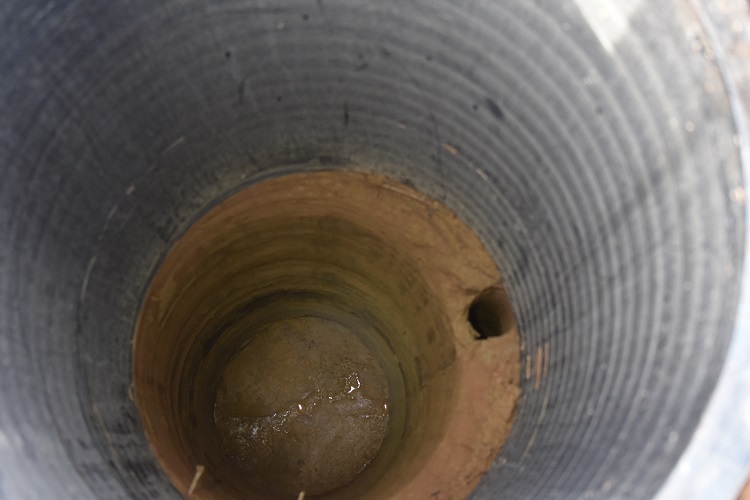 Large metal cylinder above a circular hole of dirt.