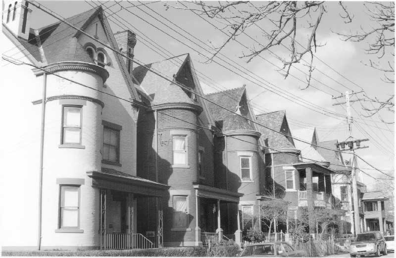 Black and white photograph of a row of two-story brick buildings.