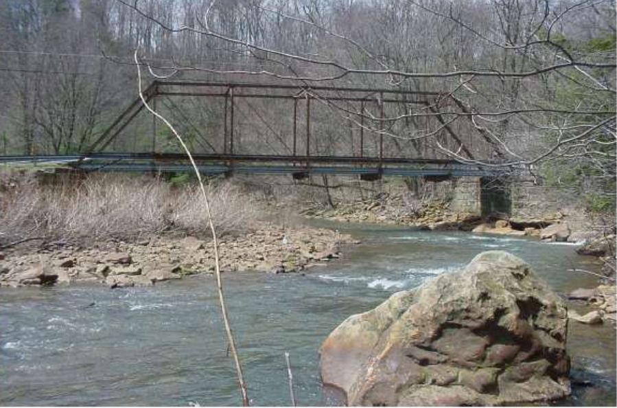 Metal bridge over water and stones in the woods.