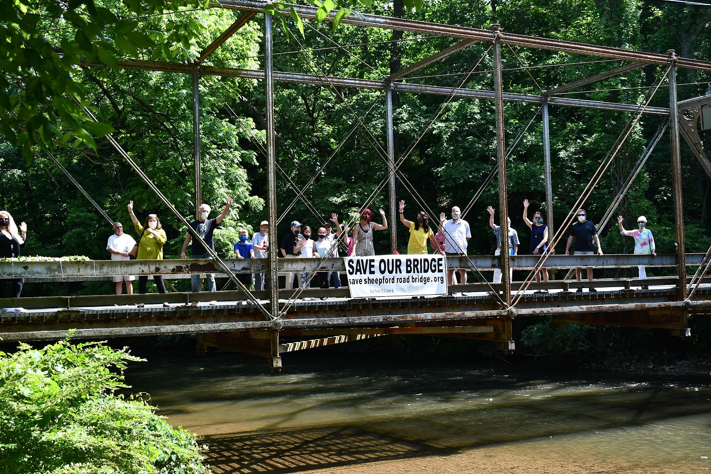 Group of people standing on a metal bridge over water.