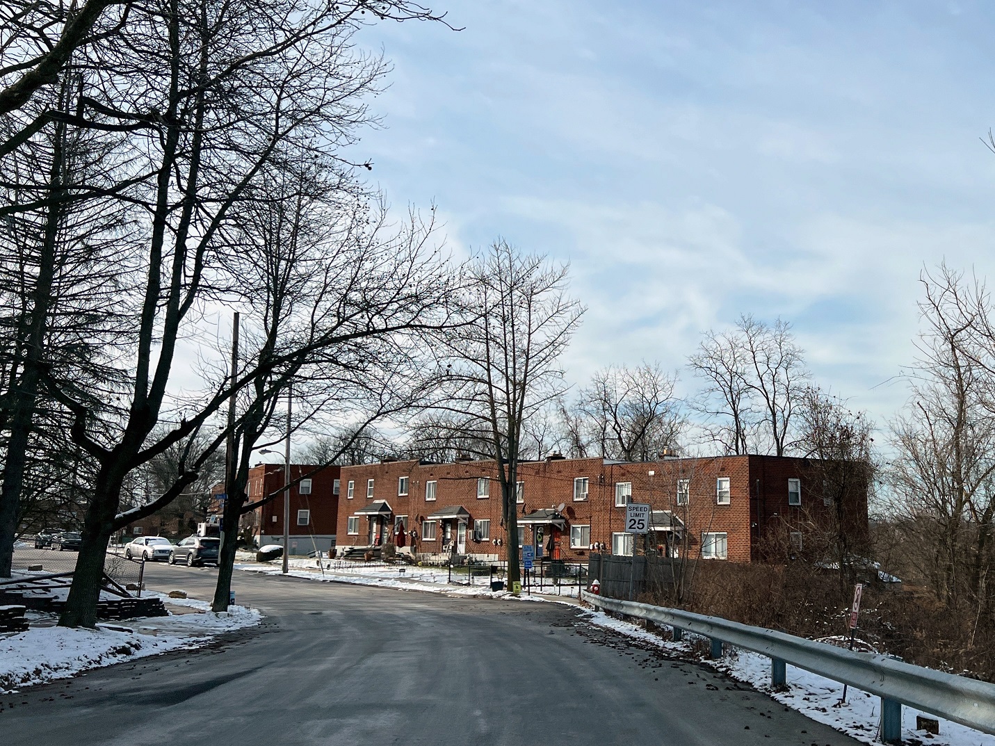 Row of connected two-story square buildings next to road in winter.