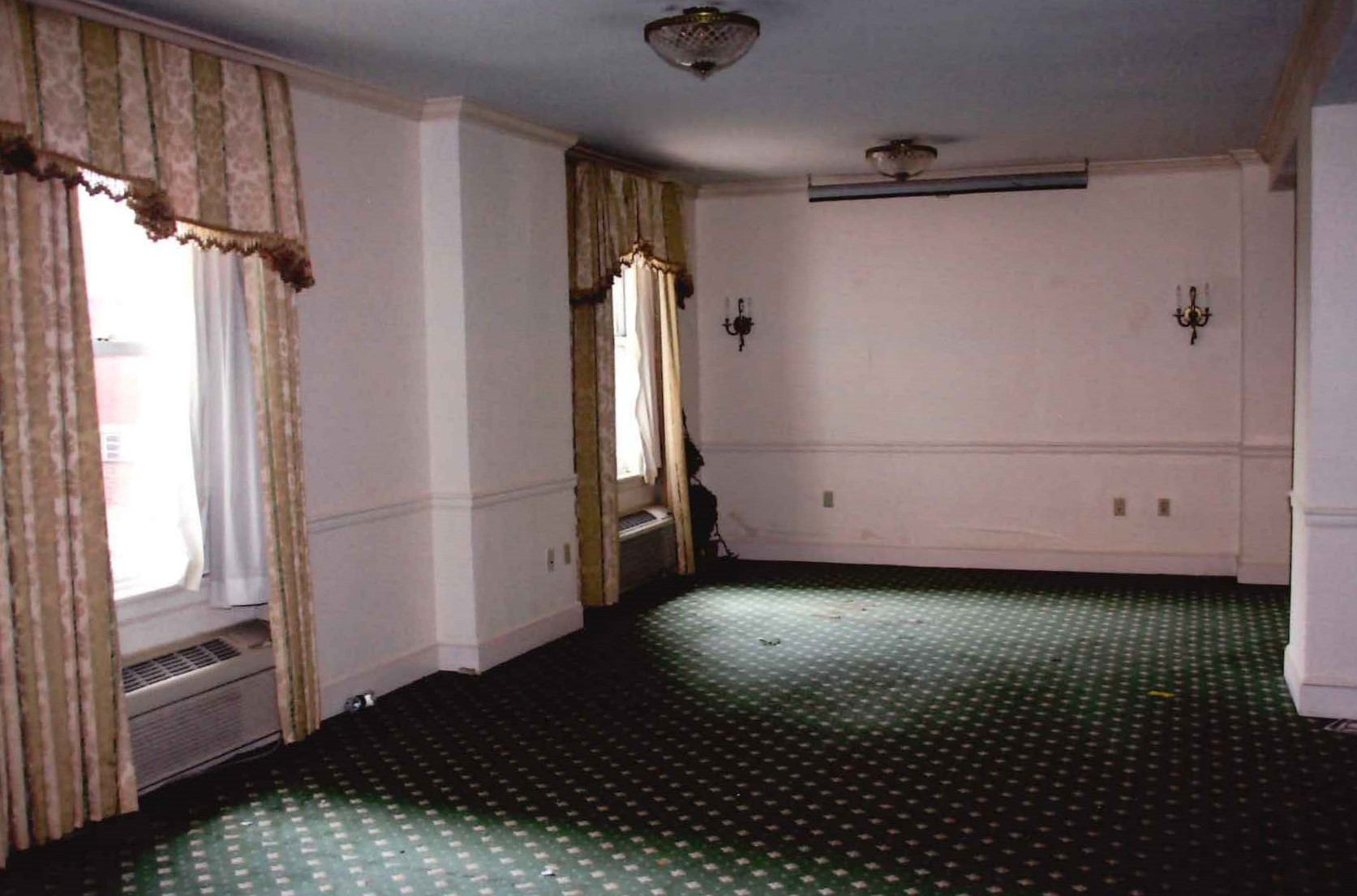 Empty room with curtains at windows.