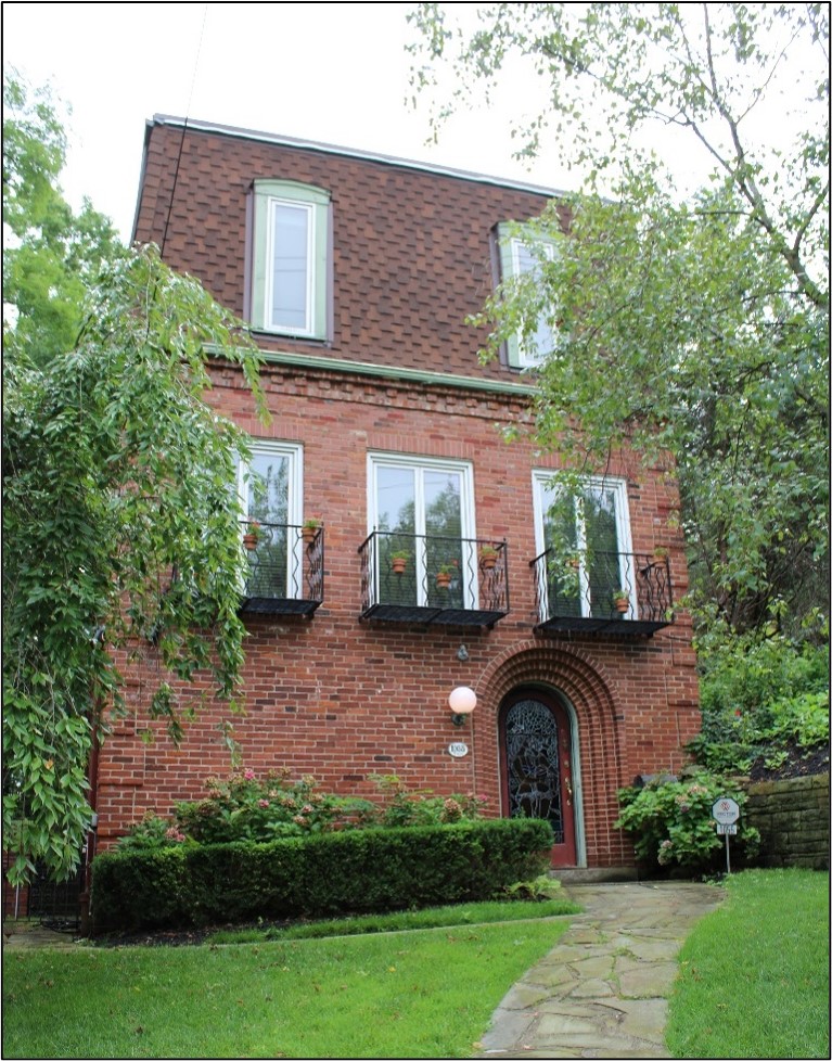 Three story brick building with arched door and three large windows at second floor.