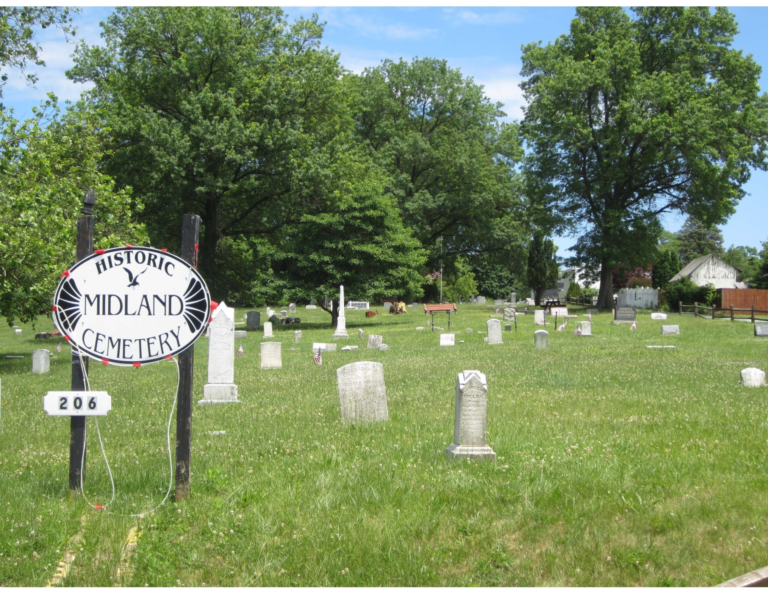 Grassy area with stone grave markers and sign.