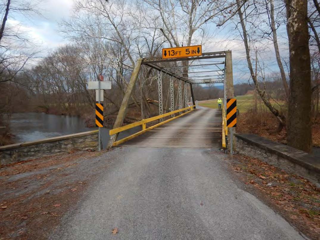 Road leading to metal bridge over water.