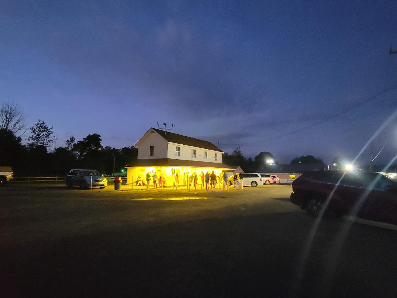 Two story building with people in parking lot at night time.