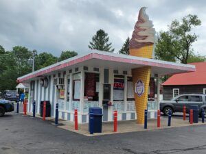 One story building with striped walls and large metal ice cream cone out front.