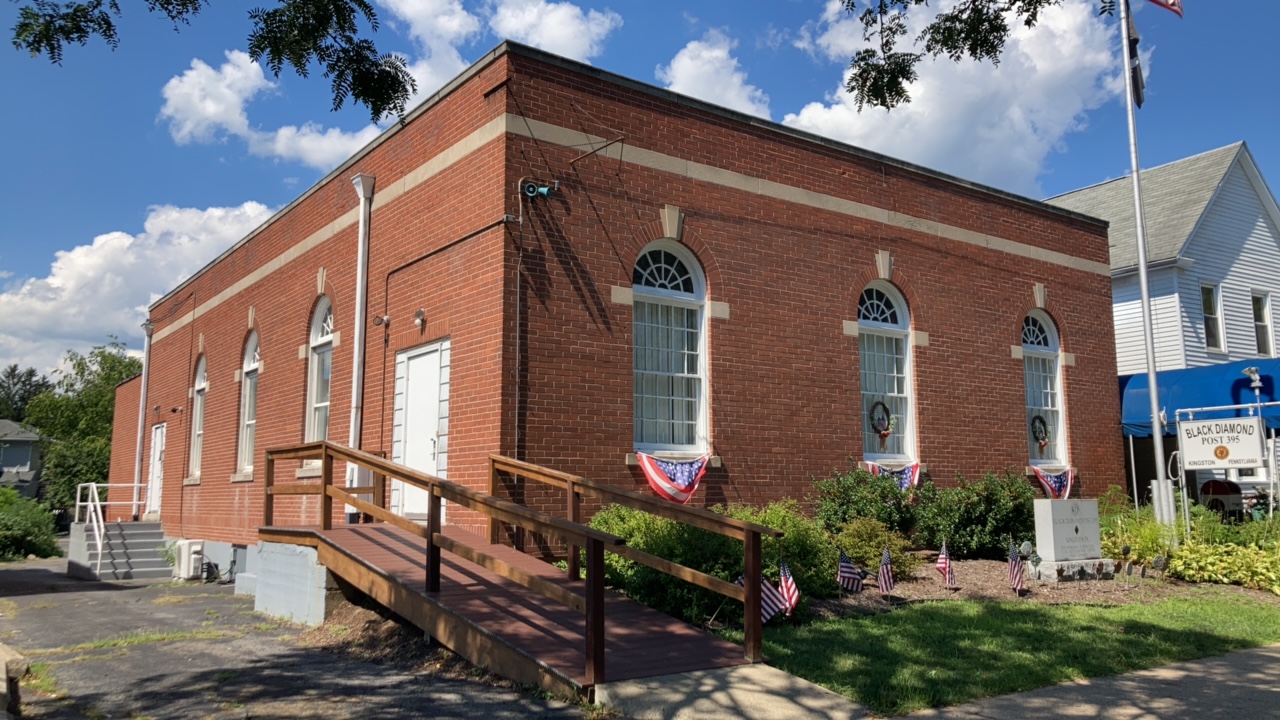 One story brick building with large arched windows, ramp, and lawn.