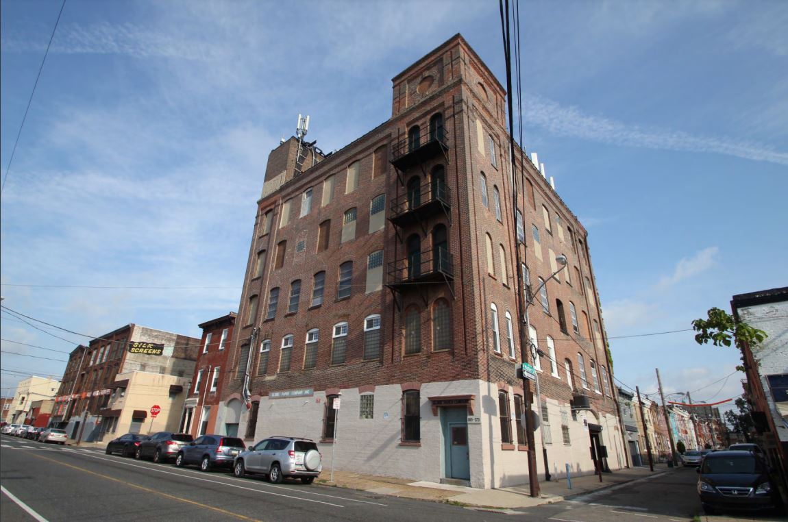 5-story brick industrial building with infilled and glass block windows and painted first floor.