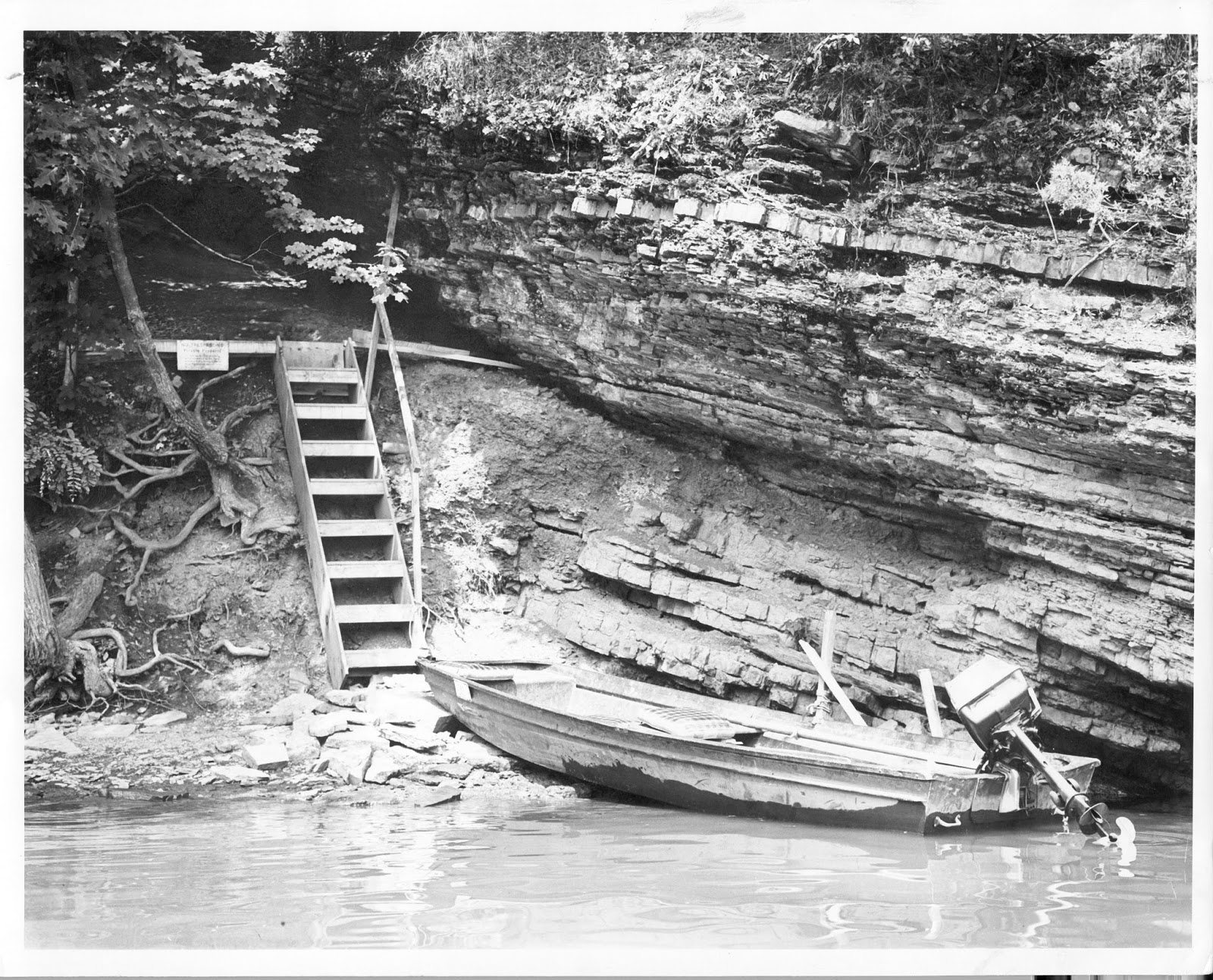 Small motorboat at edge of rocky area that has a ladder leading to higher ground.