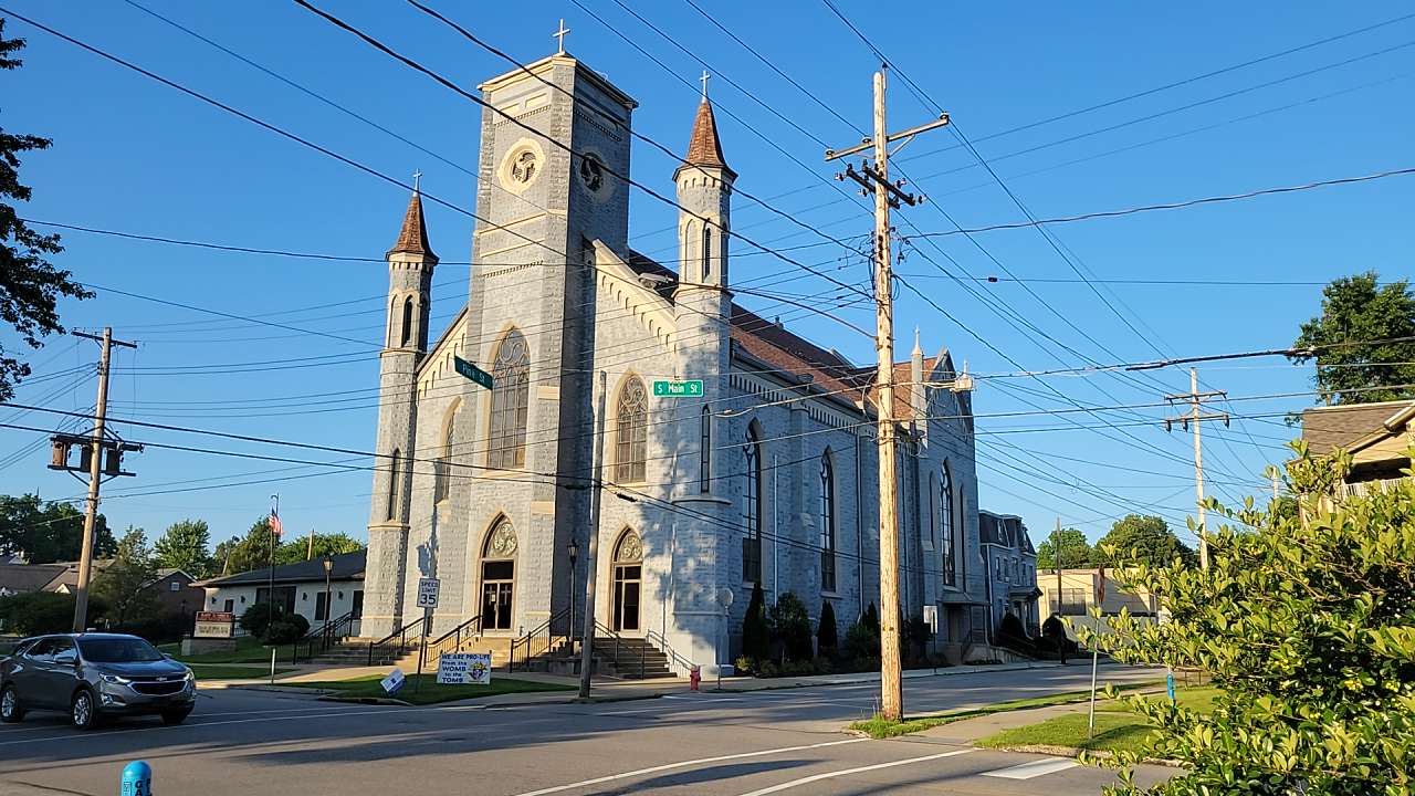 Gray stone Gothic Revival church at an intersection.
