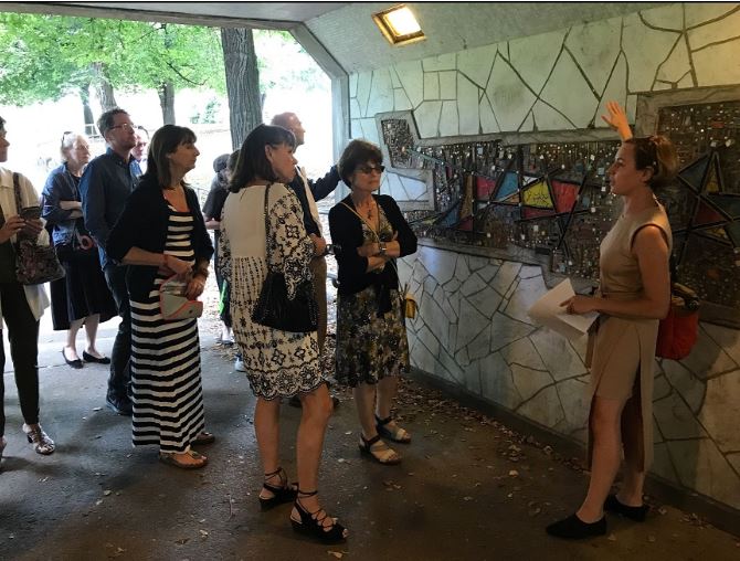 Group of people standing in a tunnel looking at woman pointing at wall.