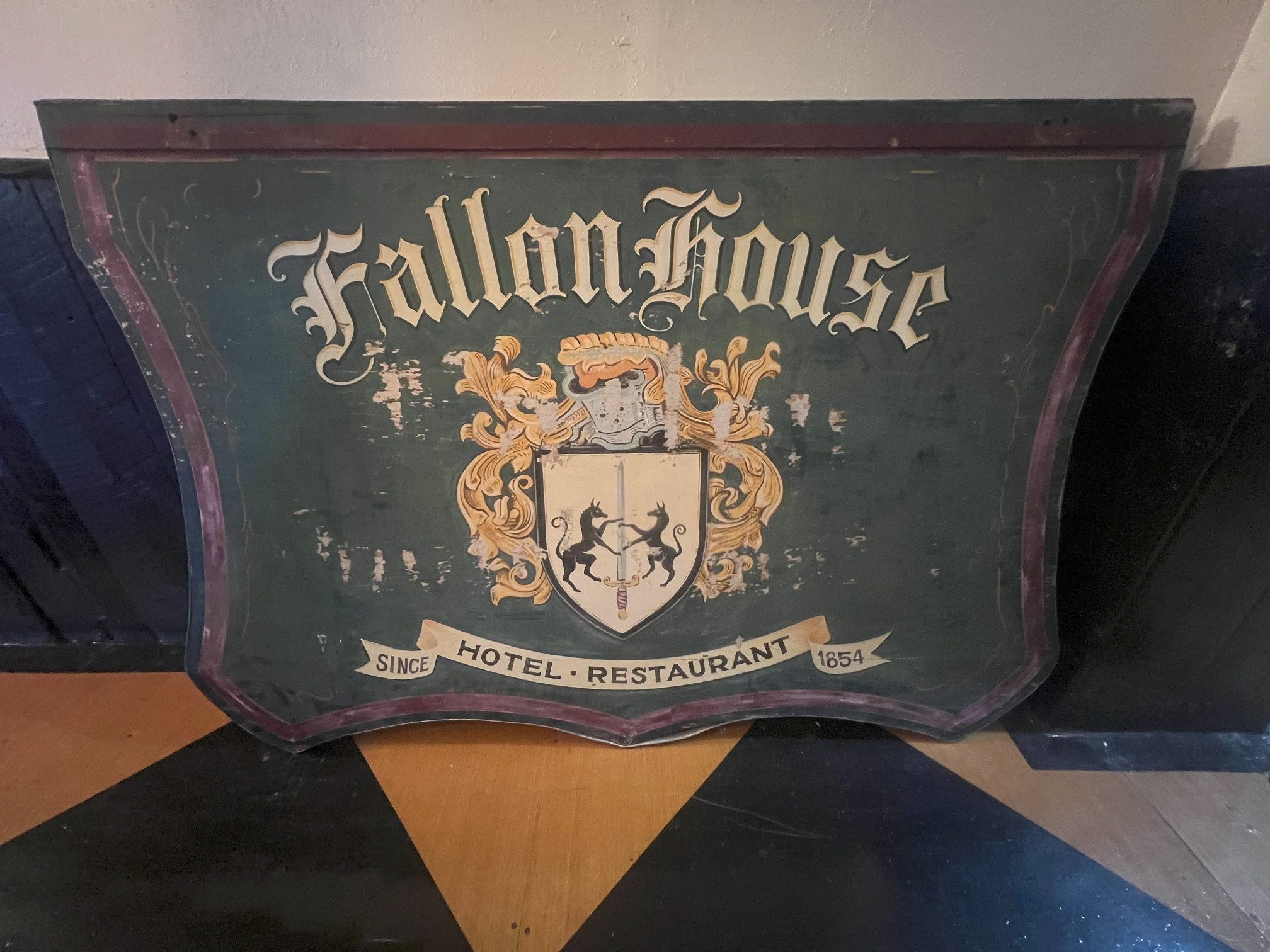 Wooden sign with words "Fallon House" above a decorative coat of arms. The words "Hotel Restaurant Since 1854" at the bottom.