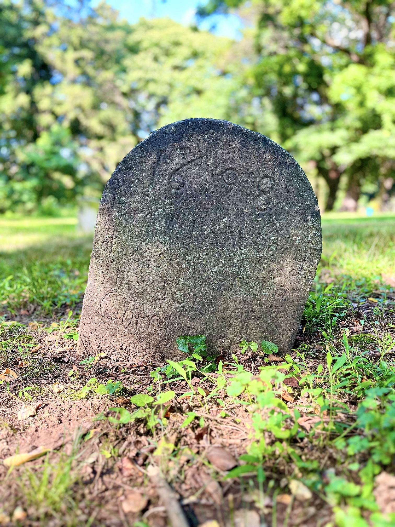 Rounded stone marker with writing set in ground.